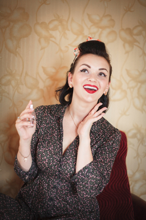 Girl with perfume. Closeup beautiful young woman pretty smiling pinup girl holding bottle of perfume and smelling aroma.の写真素材
