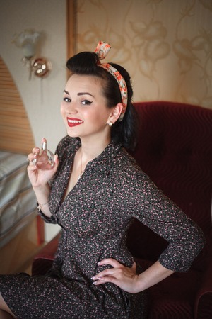 Girl with perfume. Closeup beautiful young woman pretty smiling pinup girl holding bottle of perfume and smelling aroma.の写真素材