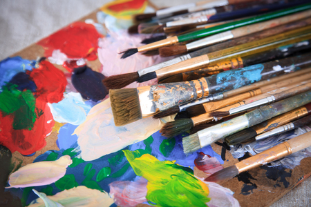Multicolored palette and many different old brushes.の写真素材