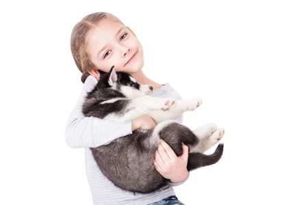 Cute little girl hugging a husky puppy, isolated on a white background.の写真素材