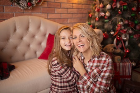 Beautiful young mother with her daughter in the New Year's interior near the Christmas tree. The concept of the winter holidays: New Year and Christmasの写真素材