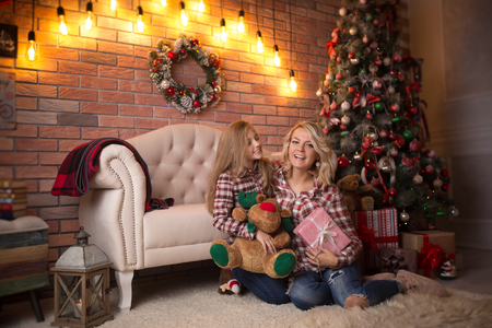 Beautiful young mother with her daughter in the New Year's interior near the Christmas tree. The concept of the winter holidays: New Year and Christmasの写真素材
