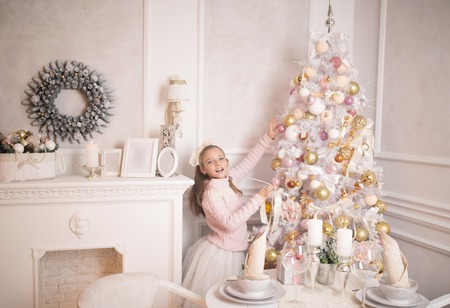 Merry Christmas celebration. Beautiful little girl in a dress standing near the Christmas tree. Winter holidays. Happy New Year.の写真素材