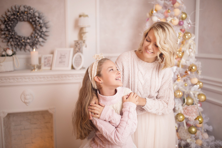 Beautiful young mother with her daughter in the New Year's interior near the Christmas tree. The concept of the winter holidays: New Year and Christmasの写真素材