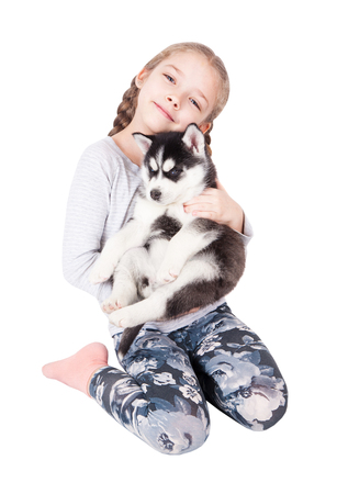 Cute little girl hugging a husky puppy, isolated on a white background.の写真素材