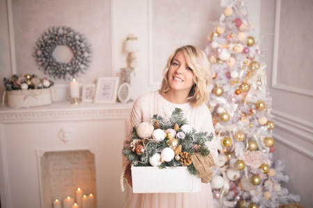 Young beautiful blonde woman decorates the Christmas tree toys. Christmas and new year concept.の写真素材
