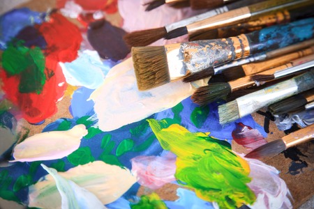 Multicolored palette and many different old brushes.の写真素材