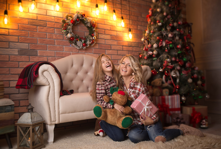 Beautiful young mother with her daughter in the New Year's interior near the Christmas tree. The concept of the winter holidays: New Year and Christmasの写真素材