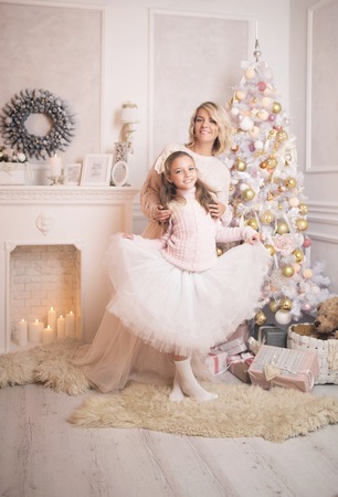 Beautiful young mother with her daughter in the New Year's interior near the Christmas tree. The concept of the winter holidays: New Year and Christmasの写真素材