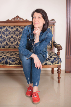 Beautiful casual woman smiling on a white background, sitting on a sofa.の写真素材