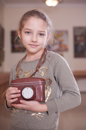Girl with a retro camera in the case, studio shot.の写真素材