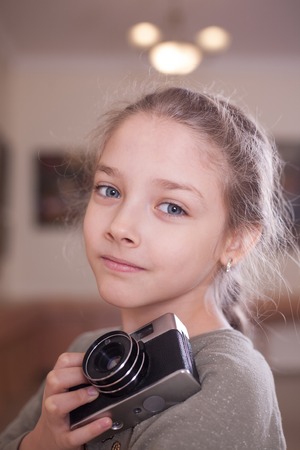 Girl with a retro camera makes a photo, studio shot.の写真素材