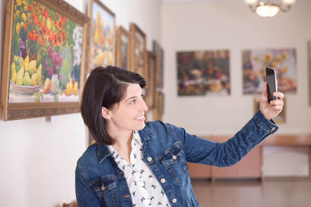 Portrait of a young woman taking a selfie in an art gallery or museum.の写真素材