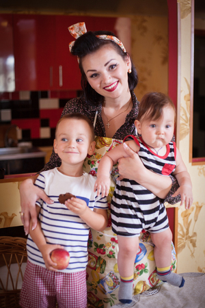 Portrait of mother and two sons in the interior of the kitchen, shot in retro style. Studio shot, home interior.の写真素材