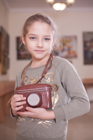 Girl with a retro camera in the case, studio shot.の写真素材