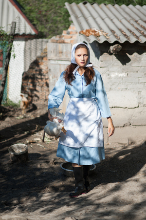A woman in a village dressed in country style is holding a goose. Shooting in retro style.の写真素材