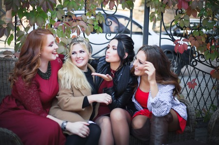 Four women have fun talking when they meet in the fall in an outdoors cafe.の写真素材