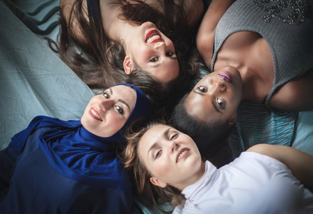 Four girls of different nationalities lying, studio shot. Positive emotions.の写真素材