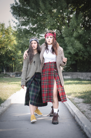 Two informally dressed girls walking down the street with cigarettes. Teenage problems.の写真素材