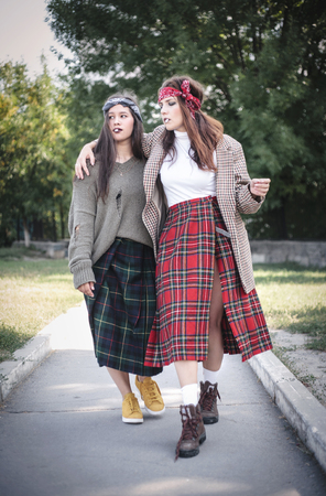 Two informally dressed girls walking down the street with cigarettes. Teenage problems.の写真素材