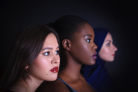 Makeup. Three women portrait. Arabic, asian and afro-american women posing in studio over black background. Fashion, beauty, glam, youth.の写真素材