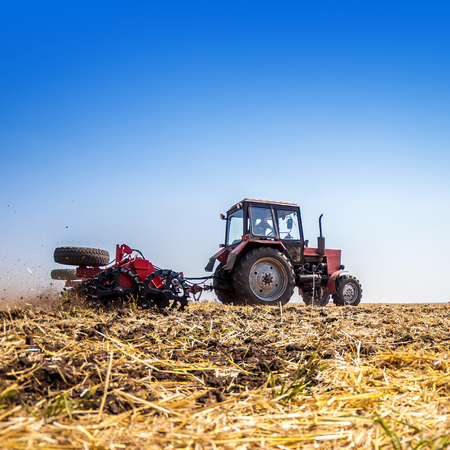 The tractor plows the field, cultivates the soil for sowing grain. The concept of agriculture and agricultural machinery.の写真素材