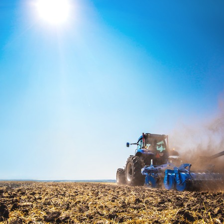 The tractor plows the field, cultivates the soil for sowing grain. The concept of agriculture and agricultural machinery.の写真素材