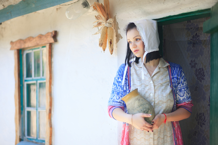 Woman young women on the background of a retro rural home with a jug in her hands.の写真素材