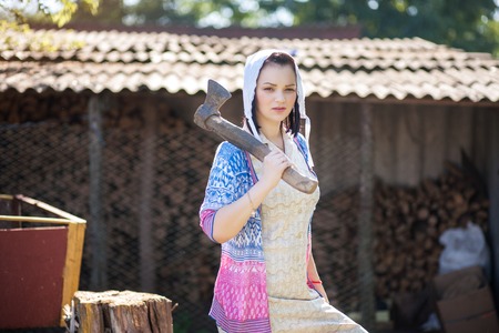 A young woman holds an ax on her hands. Portrait in retro rural style.の写真素材