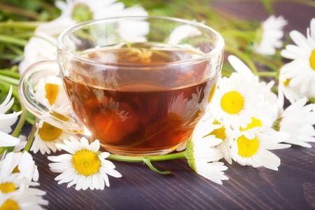 Chamomile tea in a transparent cup on a wooden table. The concept of herbal medicine.の写真素材
