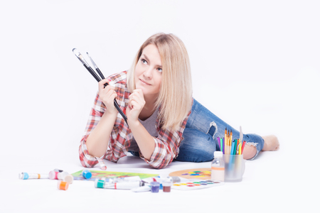 Portrait of a young woman with brushes in her hands in the studio on a white background.の写真素材