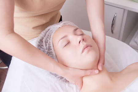 Closeup of young woman receiving neck massage from massage therapist. Real people.の写真素材