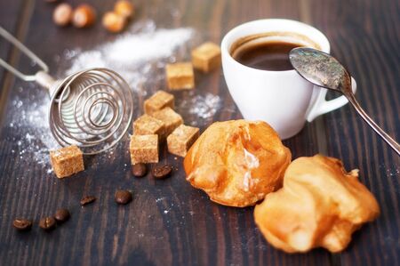 Cup of hot black coffee with home made profiteroles on a rustic wooden tableの写真素材