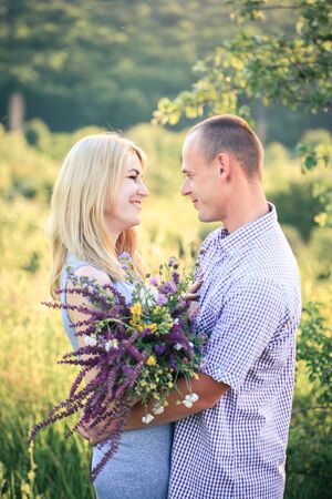 Man and woman on nature with a bouquet of flowers. Couple in love. Summer day.の写真素材