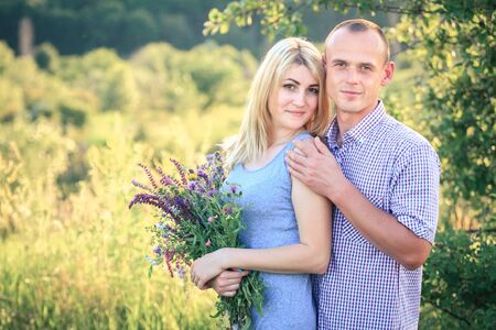 Man and woman on nature with a bouquet of flowers. Couple in love. Summer day.の写真素材
