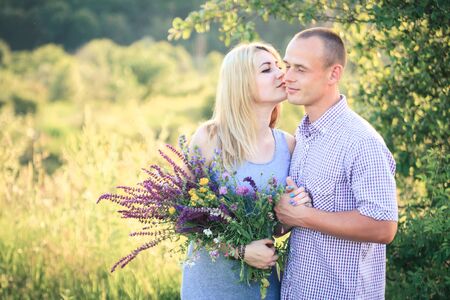 Man and woman on nature with a bouquet of flowers. Couple in love. Summer day.の写真素材