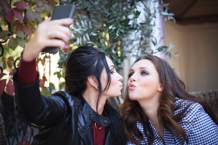 Two beautiful women taking selfie in cafe, daytimeの写真素材