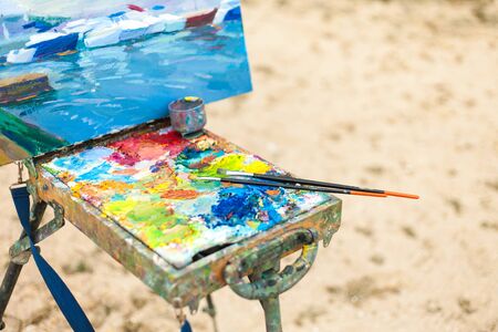 Colorful workplace of the artist with brushes and oil paints in the open air, on a beachの写真素材