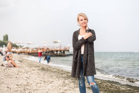 Attractive woman wearing a warm cardigan at the cold beach. Walk near sea.の写真素材