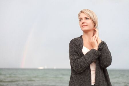 Attractive woman wearing a warm cardigan at the cold beach. Walk near sea.の写真素材