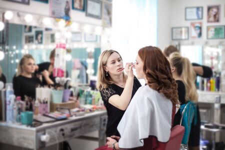 Professional makeup artist working on young woman, makes makeup in a beauty salon.の写真素材