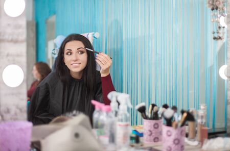 Young woman uses mascara near the mirror. Beauty and care. Studio shot.の写真素材