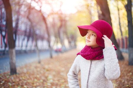 Girl in classic coat and hat in autumn park. Autumn season, fashion, children's age.の写真素材
