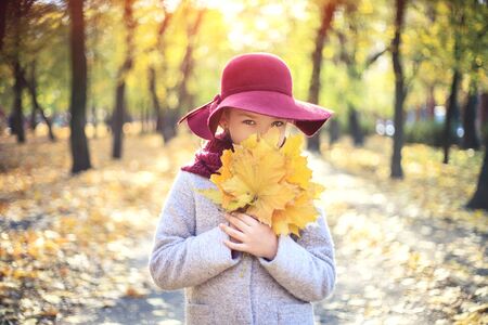 Girl in classic coat and hat in autumn park. Autumn season, fashion, children's age.の写真素材