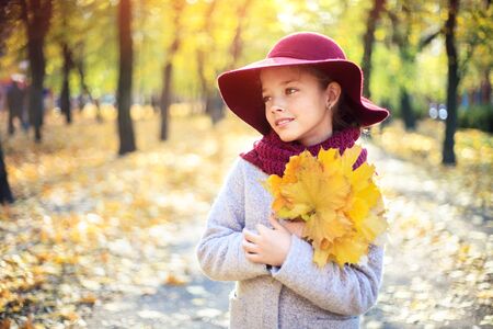 Girl in classic coat and hat in autumn park. Autumn season, fashion, children's age.の写真素材