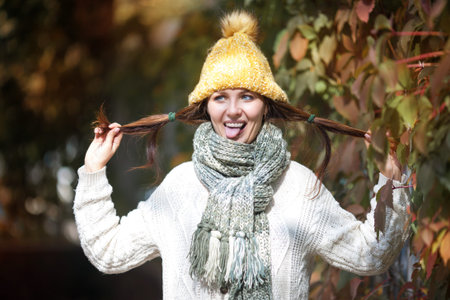 Happy lifestyle portrait of a beautiful young model girl with a sweet smile in a warm autumn scarf.
