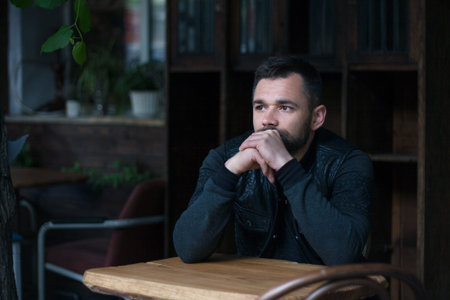 Portrait of a bearded young man in the interior. Street style clothing.