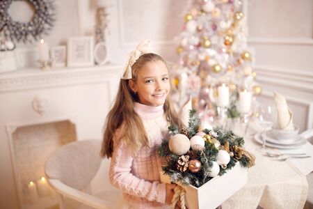 Merry Christmas celebration. Beautiful little girl in a dress standing near the Christmas tree. Winter holidays. Happy New Year.の写真素材
