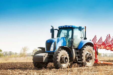 The tractor plows the field, cultivates the soil for sowing grain. The concept of agriculture.の写真素材