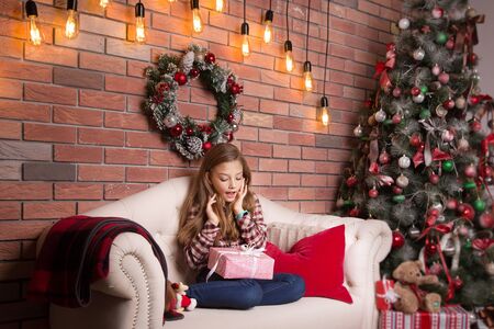 Little school age girl with a Christmas gift in her hands.の写真素材